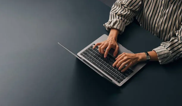 Accountant at a desk in a UAE office reviewing ledger detail on a laptop before closing the month and preparing the VAT return workings