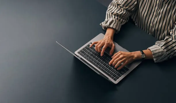 Accountant at a desk in a UAE office reviewing ledger detail on a laptop before closing the month and preparing the VAT return workings