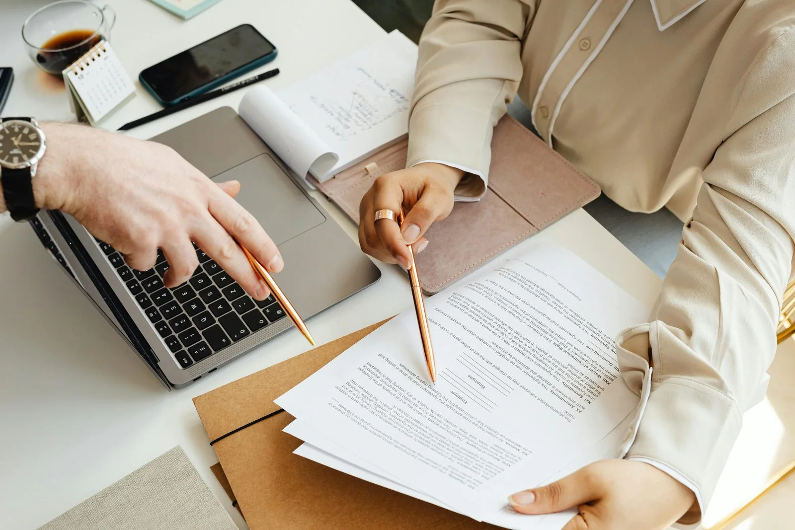 Two colleagues reviewing printed financial reports beside a laptop at a bright office desk, the monthly reporting conversation most UAE businesses either have or skip