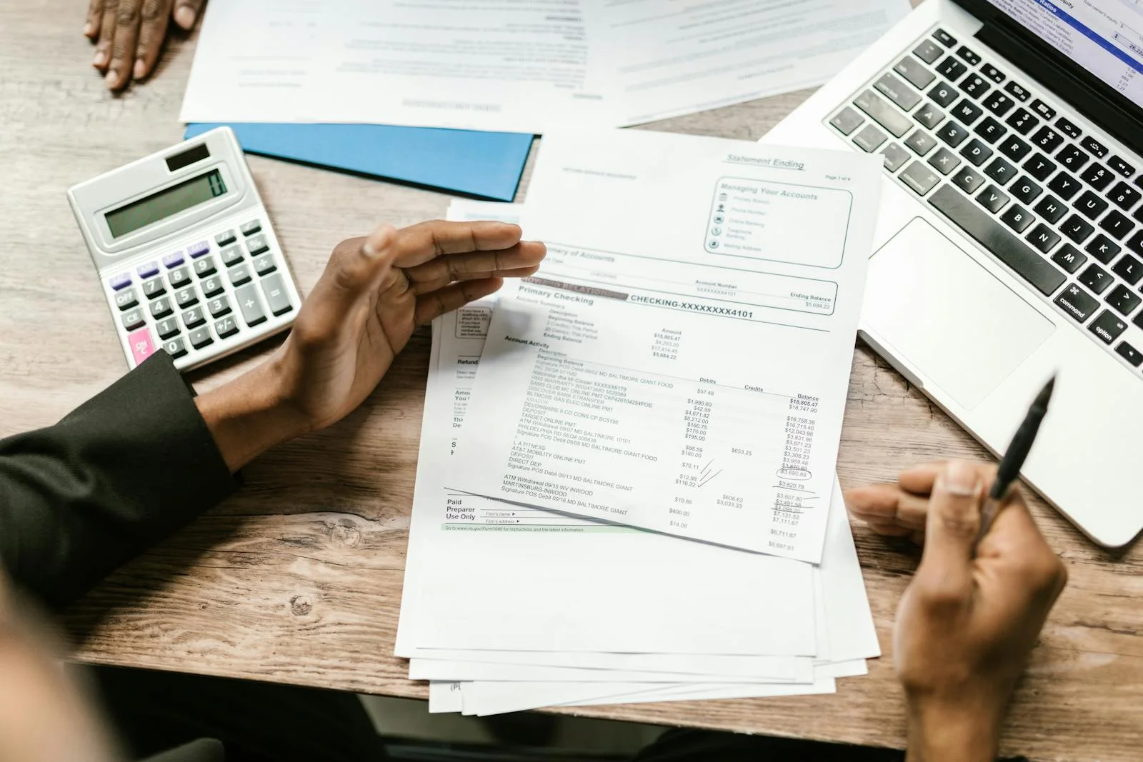 Reviewing UAE business financial statements with a calculator and laptop — accounting work Velmont Crest handles for referred clients