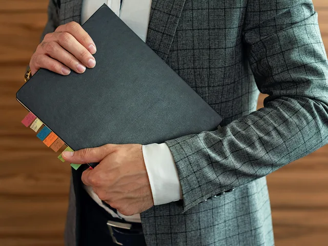 Advisor holding a tabbed annual audit folder with year-end workpapers and schedules.