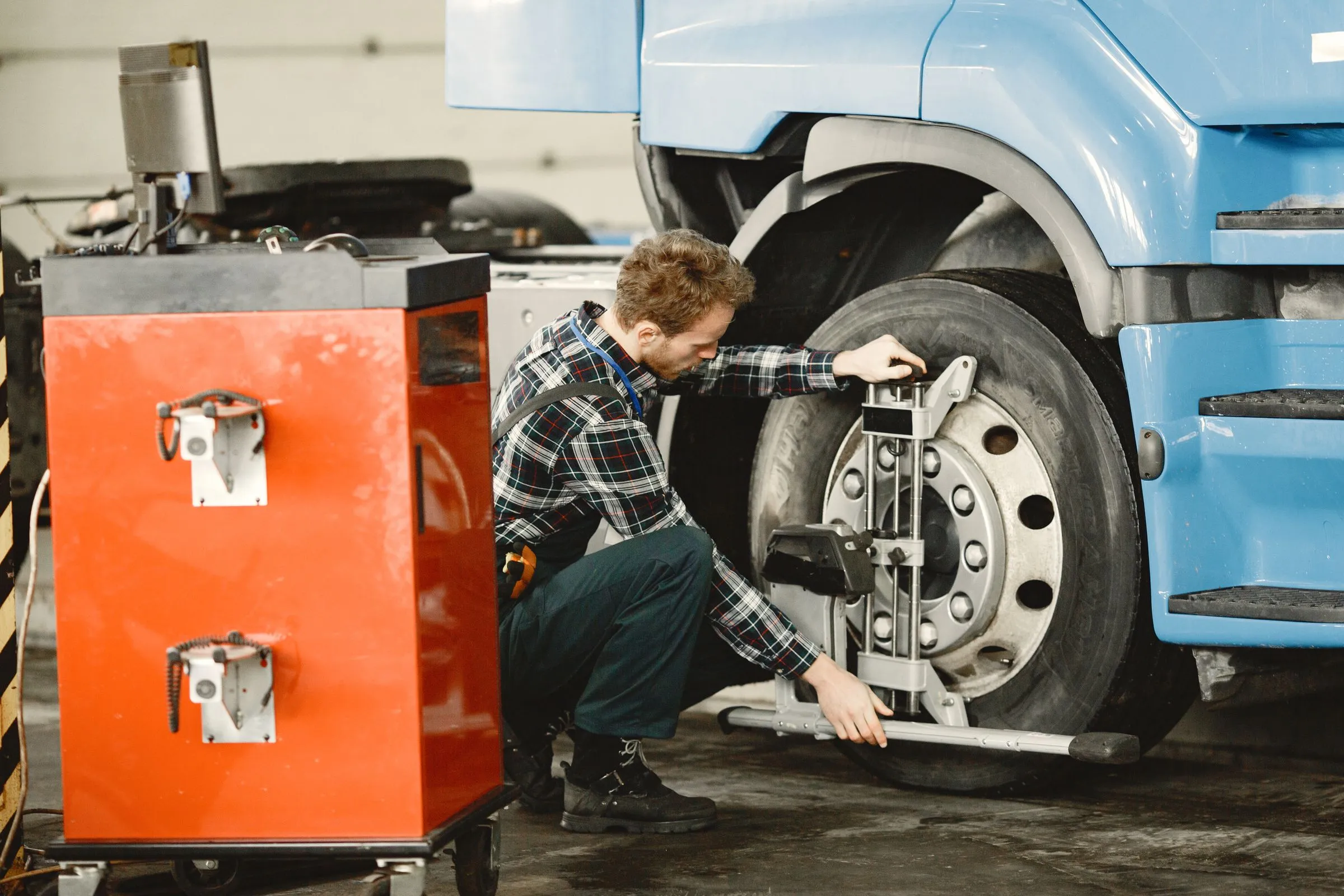 Technician working on a commercial vehicle in a workshop bay, the kind of job where cost accounting has to capture labour hours parts and overhead against a single job number